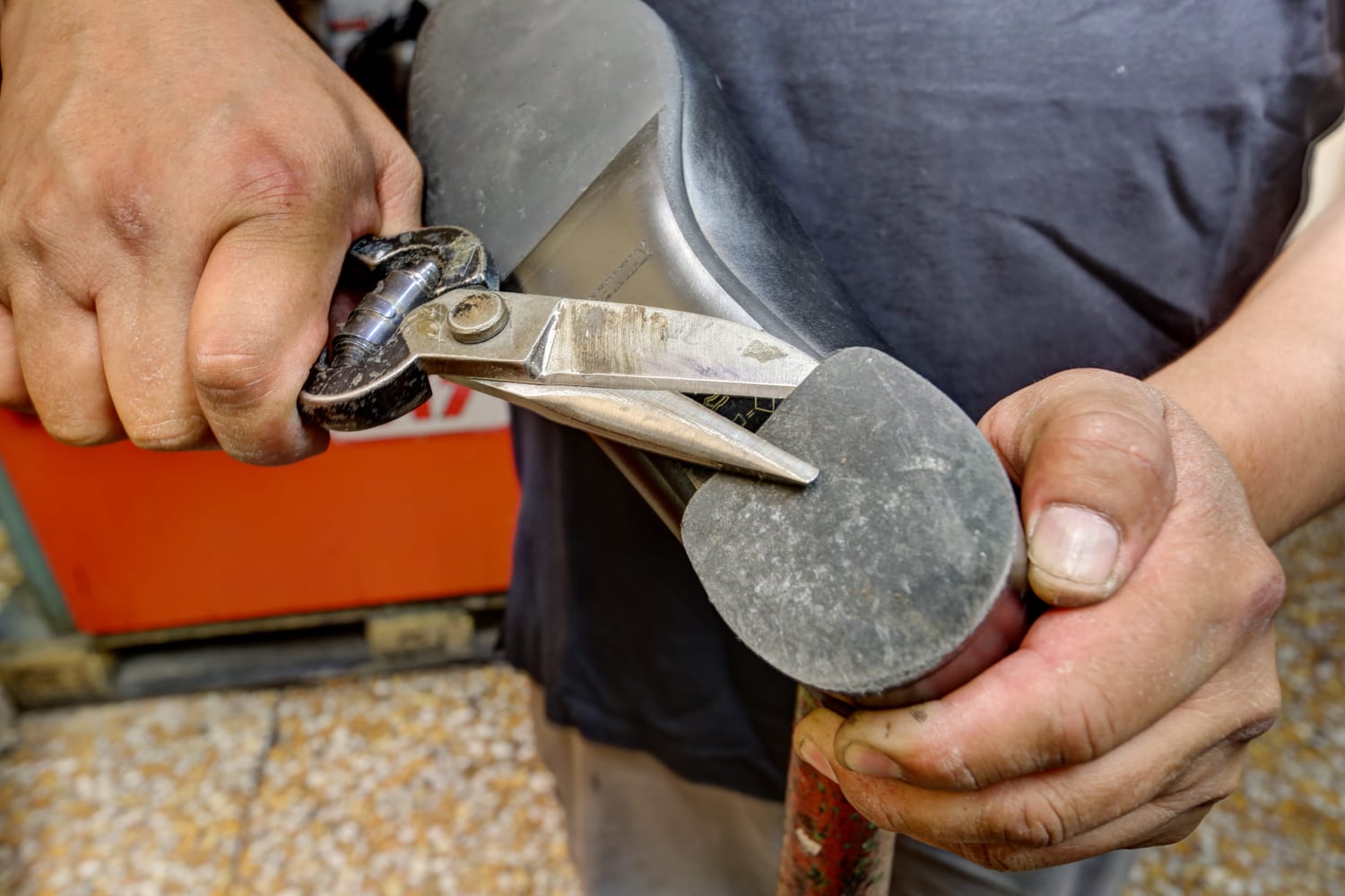 Le mani del calzolaio al banco, con le tenaglie e il martello da lavoro